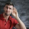 Man in Red Polo Shirt Sitting Near Chalkboard