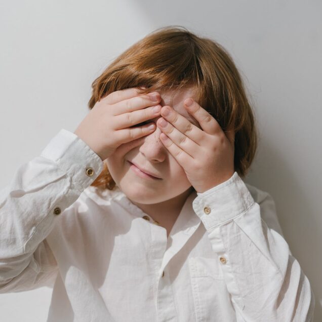 Photograph of a Boy Covering His Eyes