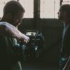 man holding camcorder with man near wall